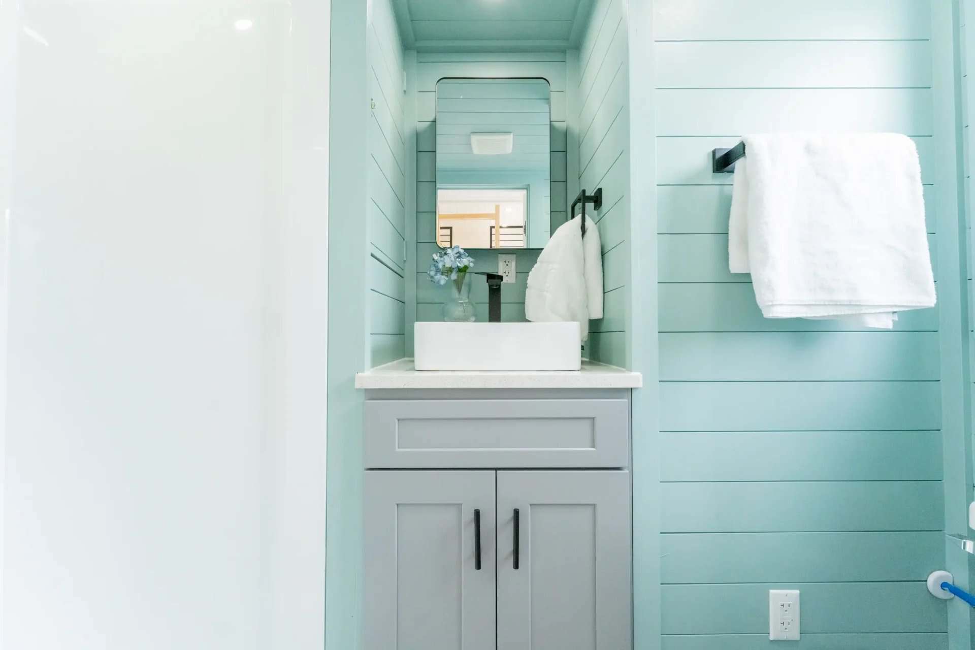 Mirrored medicine cabinet over the vessel sink in the seafoam Avalon 24 bathroom