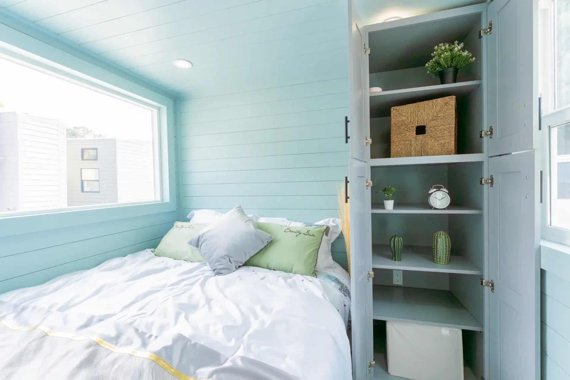 Bedroom storage cabinet with open shelves next to the bed in the Avalon 24 tiny house