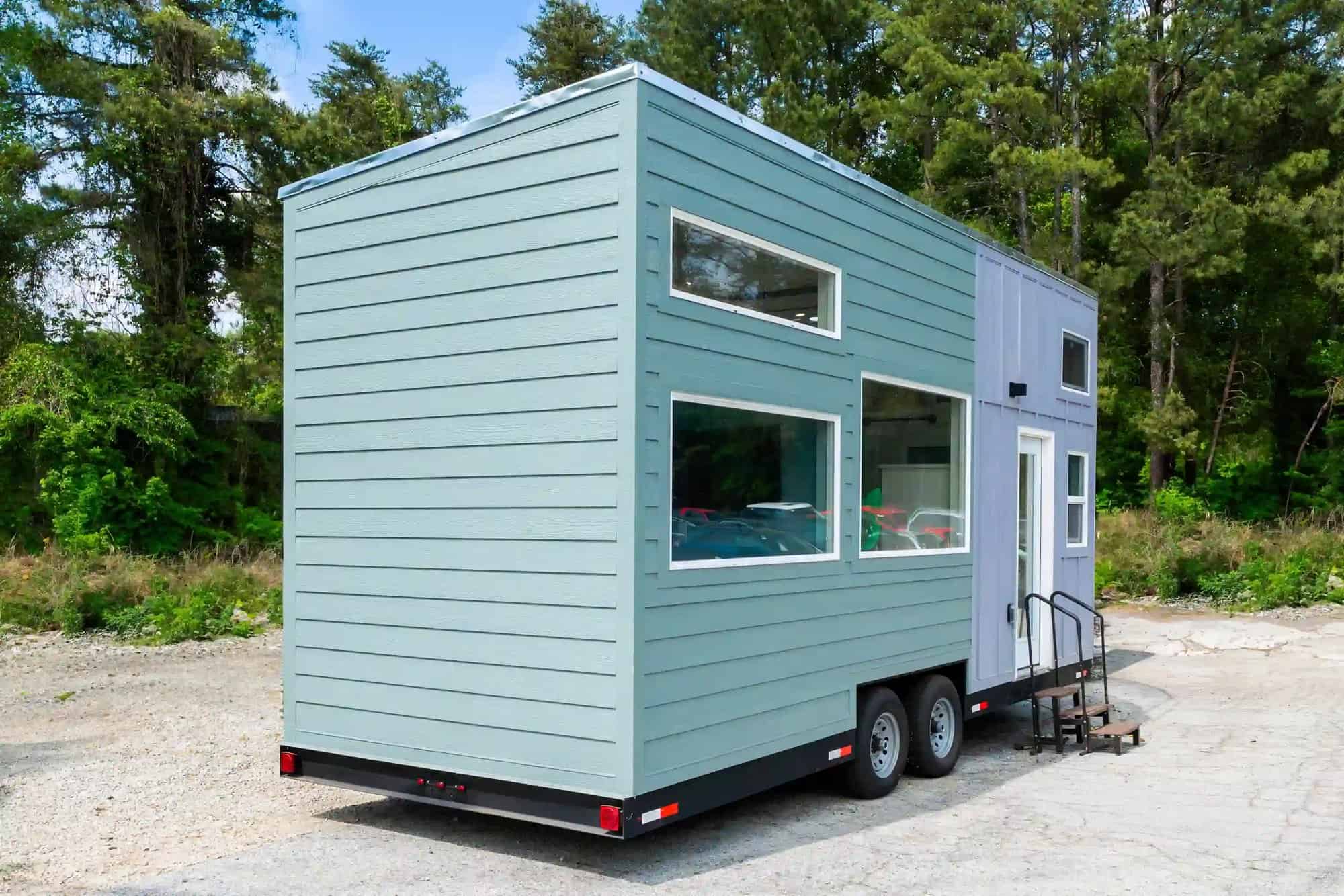 Rear corner of the Avalon 24 tiny house showing the raised roofline over the loft and double-axle trailer