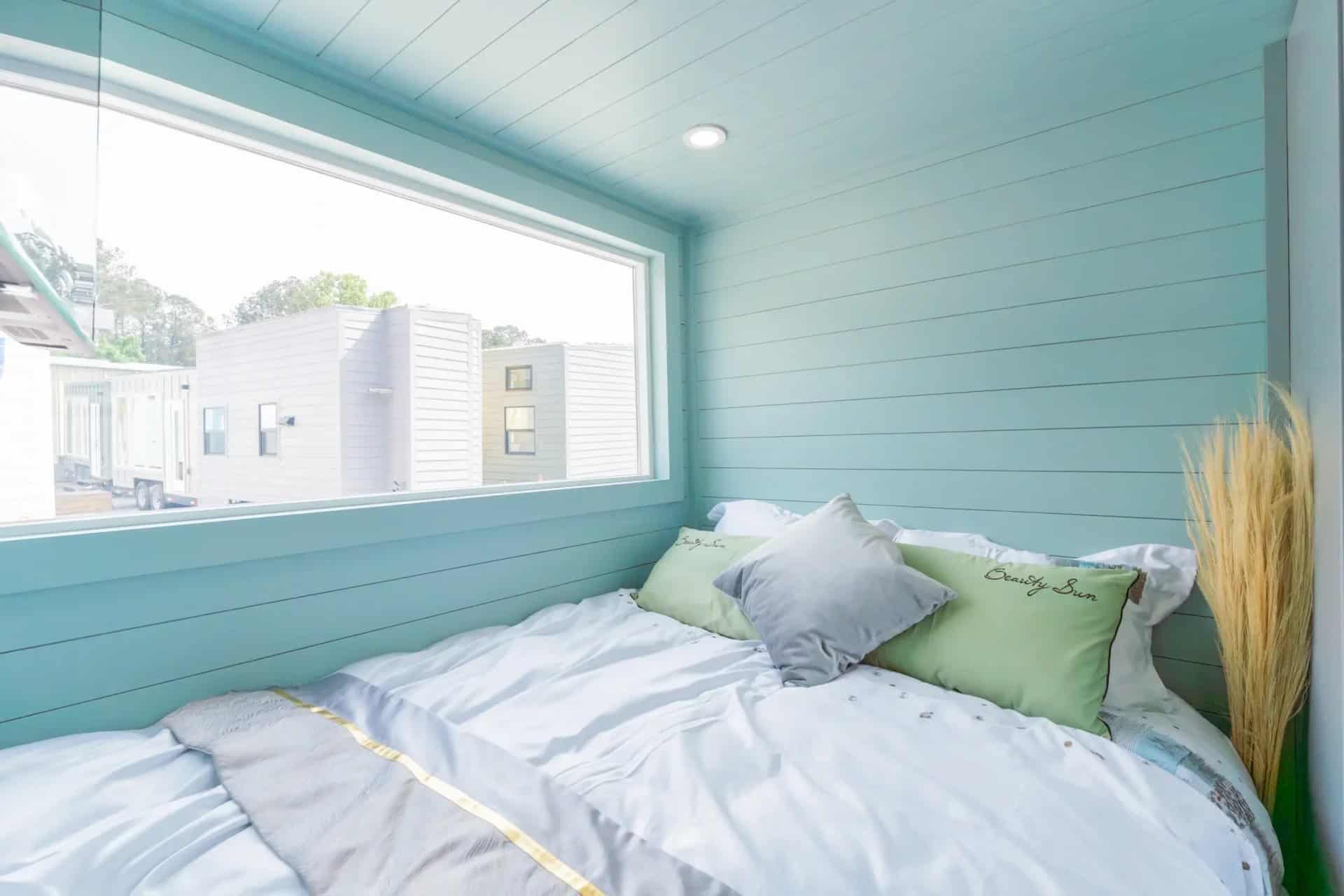First-floor bedroom in the Avalon 24 with a double bed, seafoam walls, and a large window