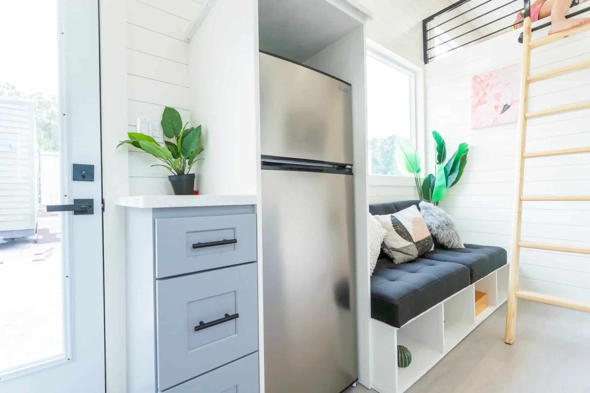 Stainless refrigerator in a built-in cabinet with three drawers beside the living room couch