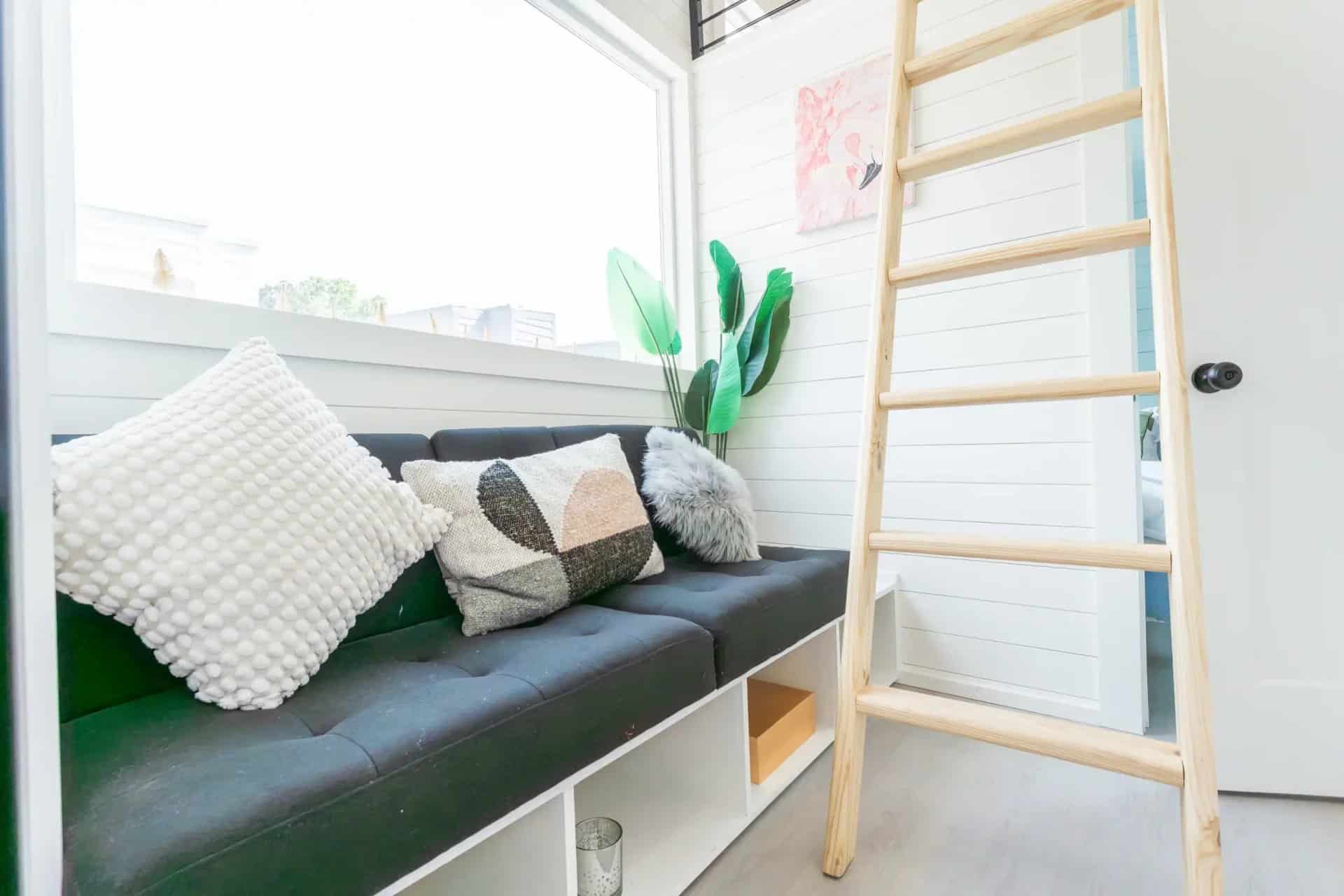Built-in couch with storage cubbies and a wooden loft ladder in the Avalon 24 living room