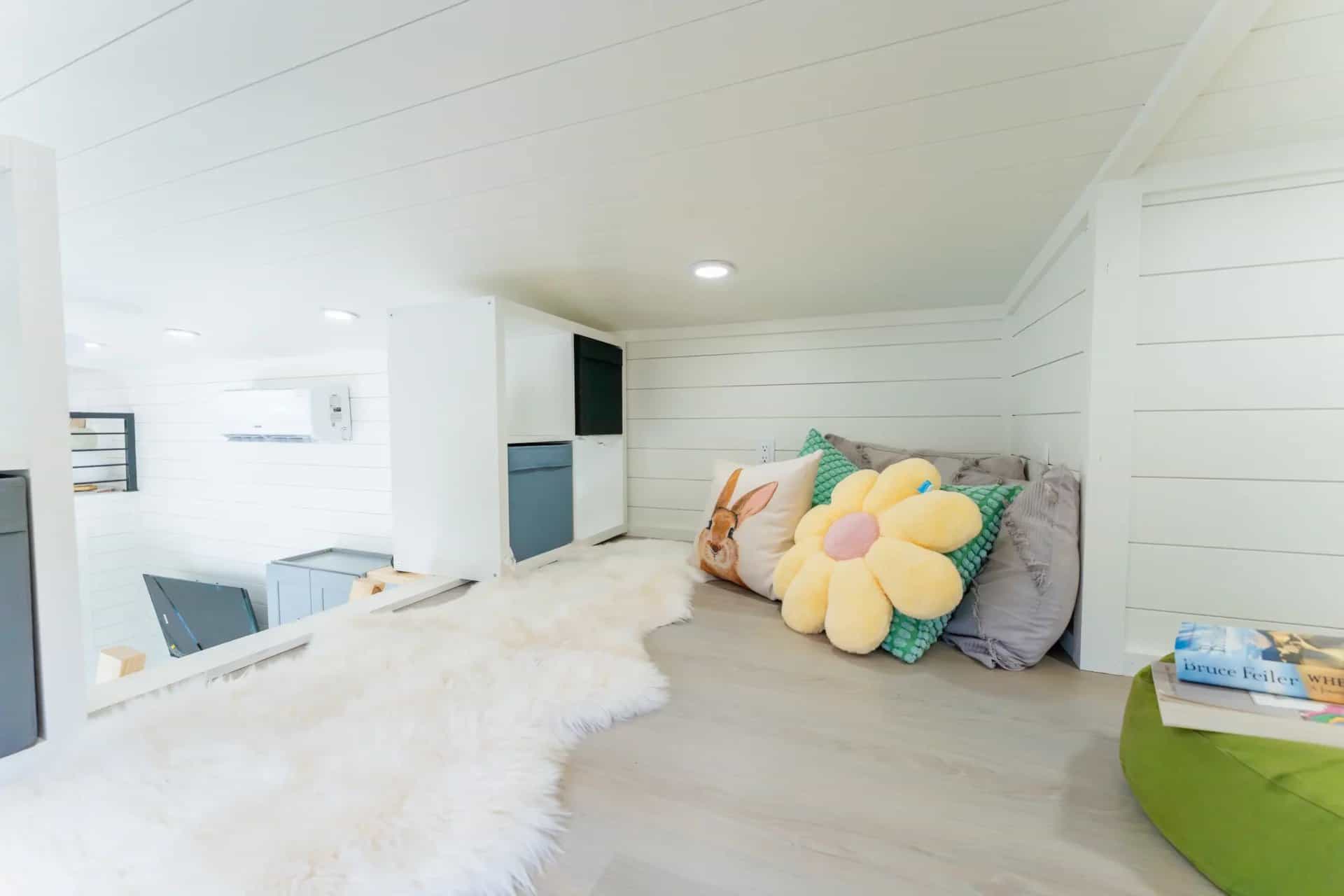 Second loft in the Avalon 24 with a sheepskin rug, floor cushions, and white shiplap walls