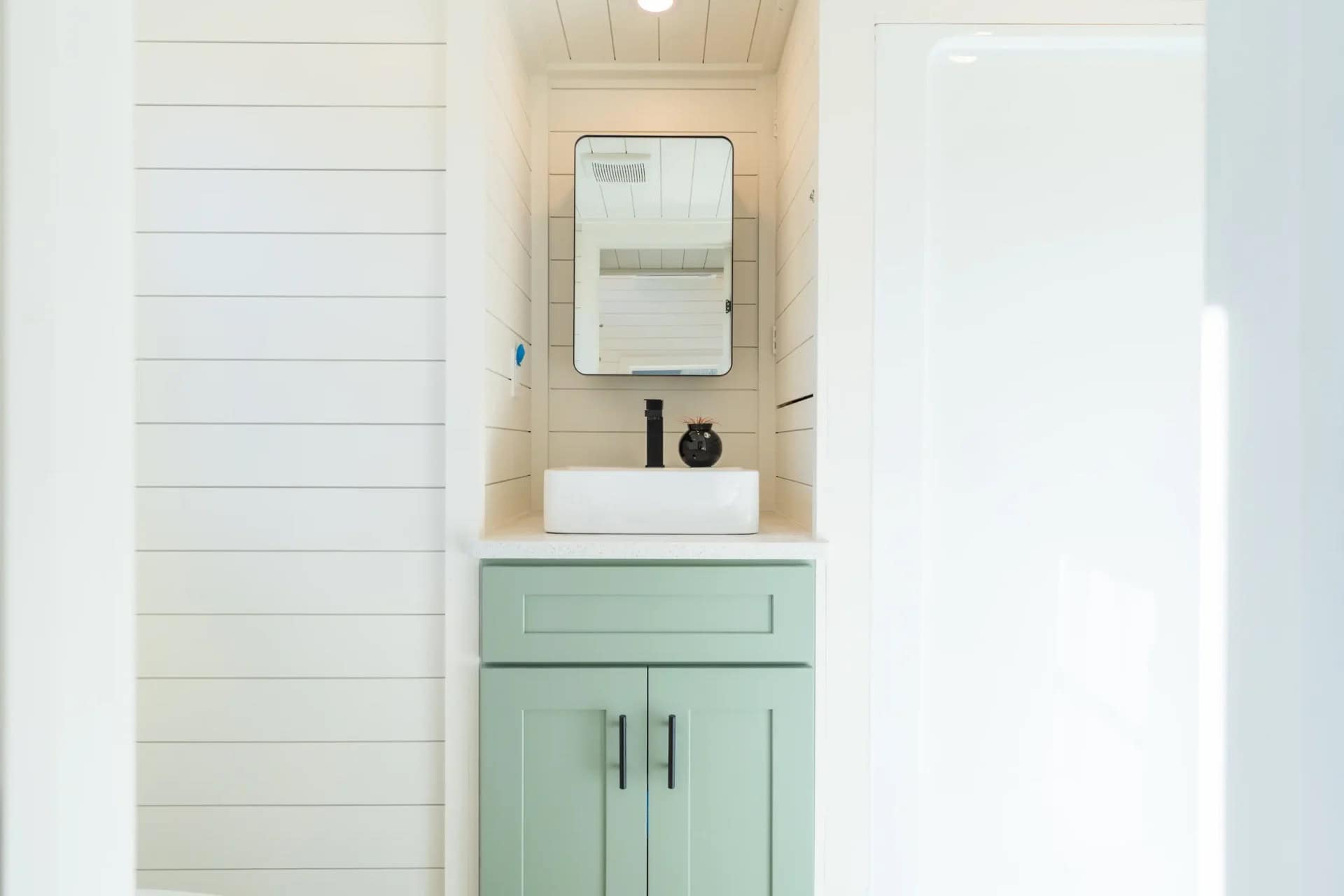 Genesis gallery bathroom: mint vanity in a shiplap alcove with a white vessel sink, black faucet and black-framed mirror above