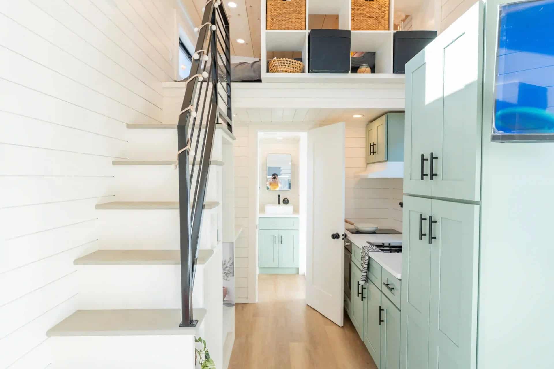 Genesis gallery interior: storage stairs, mint-green kitchen, loft cubbies, bath doorway — may be a prior Genesis build