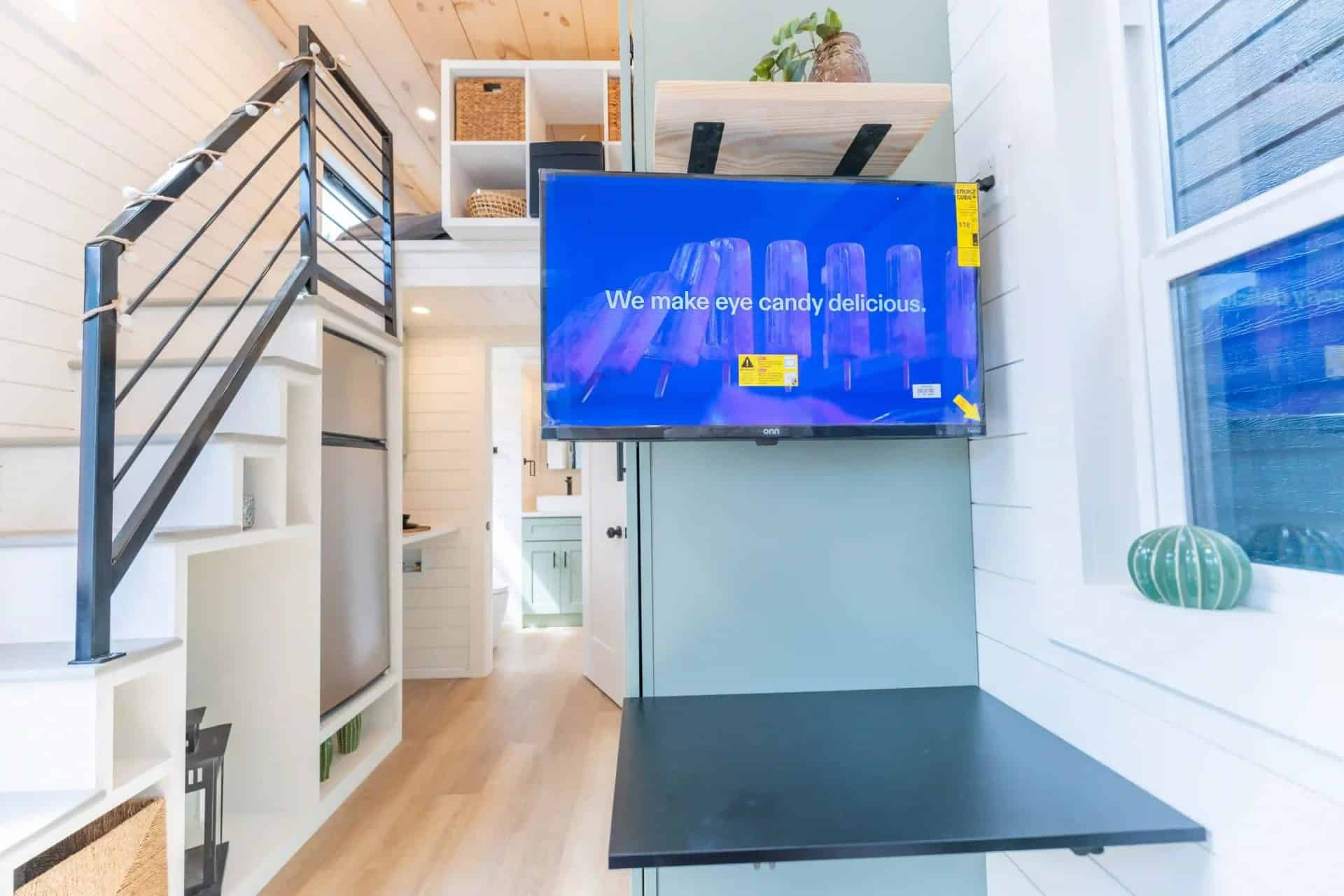 Genesis gallery interior: fridge in the stair mass, sage wall, folding desk, loft cubbies — may be a prior Genesis build