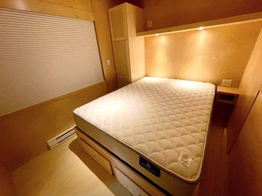 Tiny house bedroom with a comfortable mattress and cozy wooden decor.