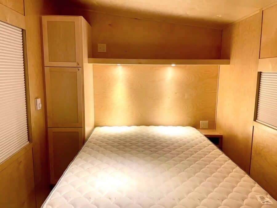 Compact tiny house bedroom with wooden interior and built-in storage.