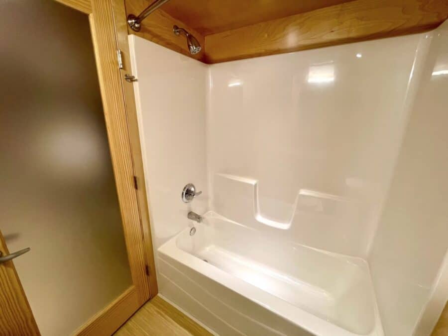 Compact tiny house bathroom with a shower and wooden accents.