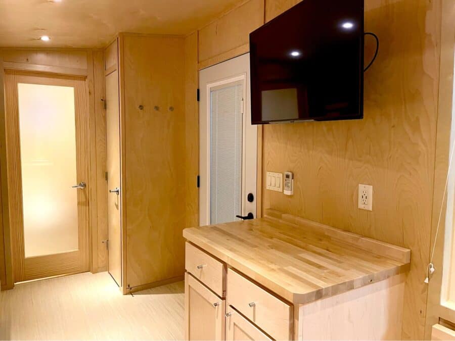 Cozy tiny house interior with wooden cabinetry and wall-mounted TV in Tampa Village.