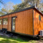 Tiny house on wheels with wooden exterior and large windows, perfect for compact living and mobility.