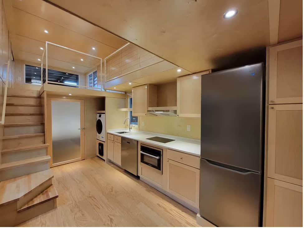 Escape eONE XL kitchen with stainless appliances, stacked washer/dryer, and stairs to the loft