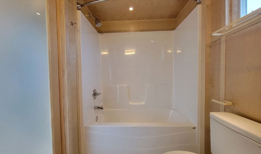 Bathroom in a tiny house with a modern bathtub and wooden accents.