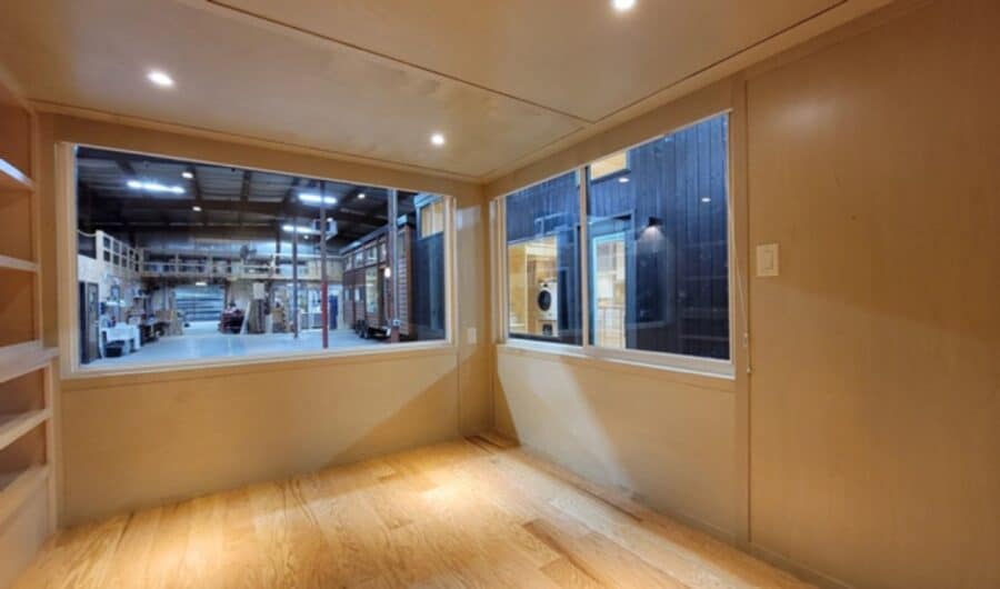 Interior of a modern tiny house with large windows and wooden floors.