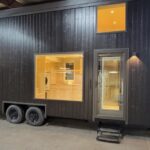 Modern black tiny house with large windows and yellow accents, showcasing innovative small space liv.