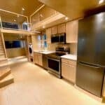 Modern tiny house kitchen with loft, appliances, and wooden finishes.