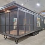 Portable tiny house with large glass windows and sleek black exterior.