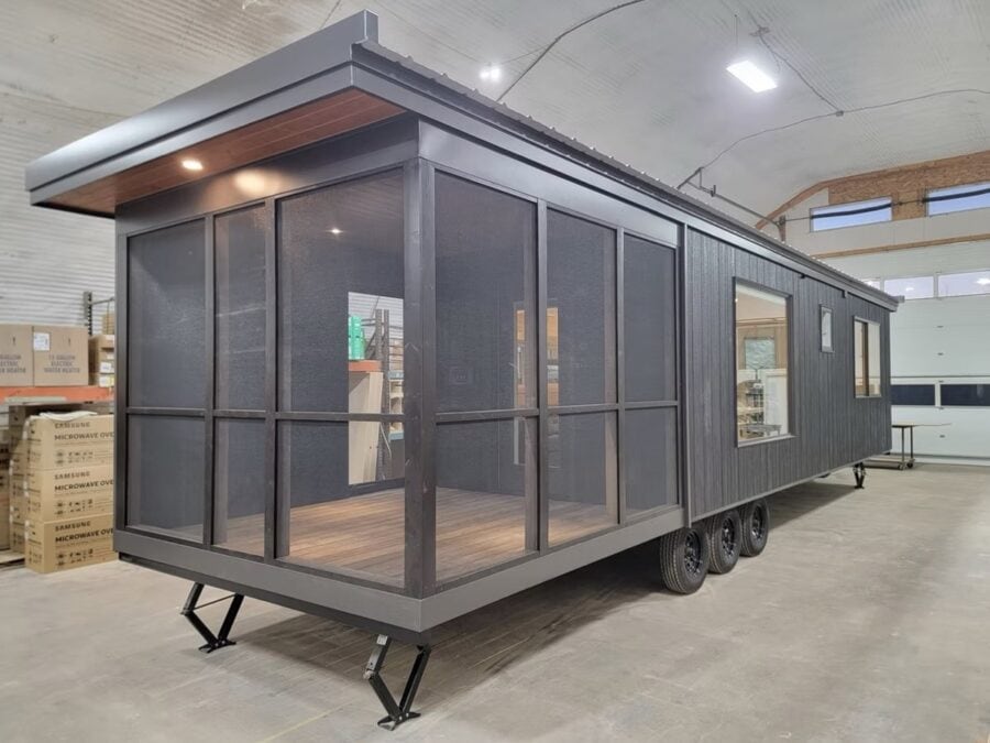 Portable tiny house with large glass windows and sleek black exterior.