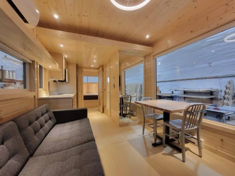 Bright, spacious tiny house interior featuring natural wood finishes and large windows for a warm, i.