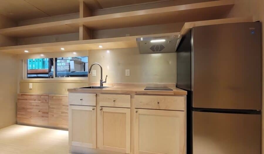Bright modern tiny house kitchen with butcher block countertops and sleek appliances.
