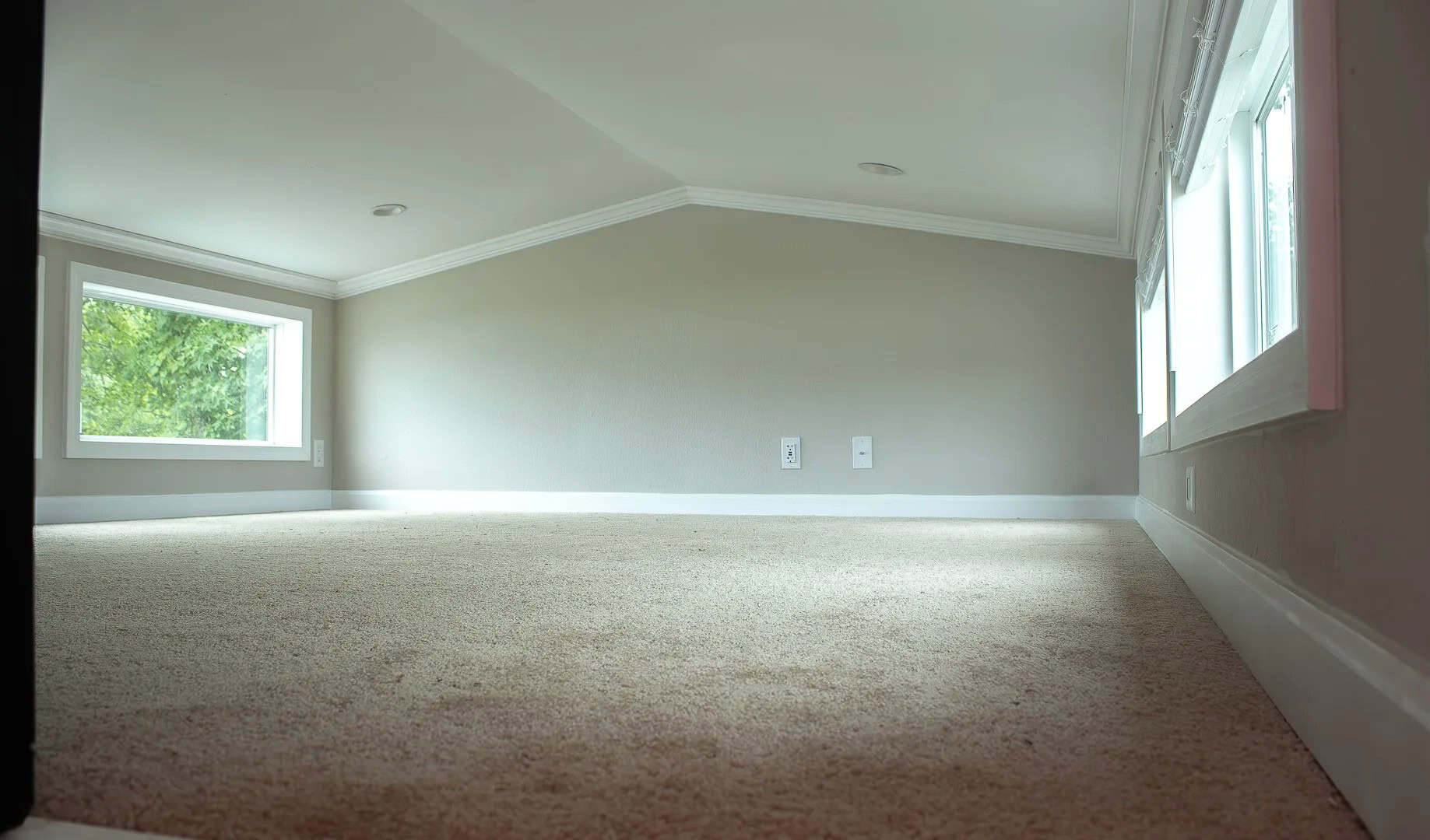 Empty carpeted loft with windows on two walls