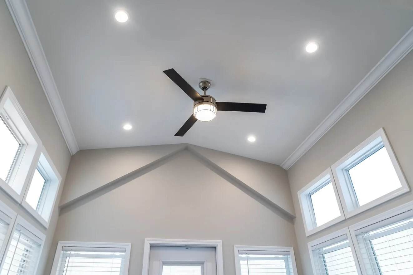 Vaulted ceiling with a ceiling fan and stacked windows above the front door
