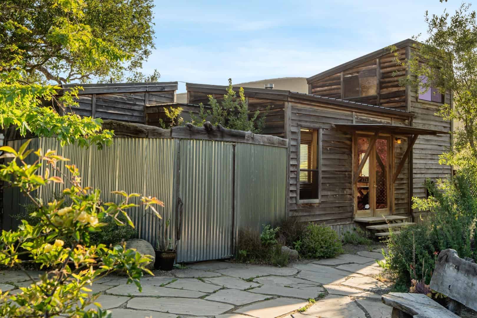 Wood exterior, a corrugated metal screen, and a stone path
