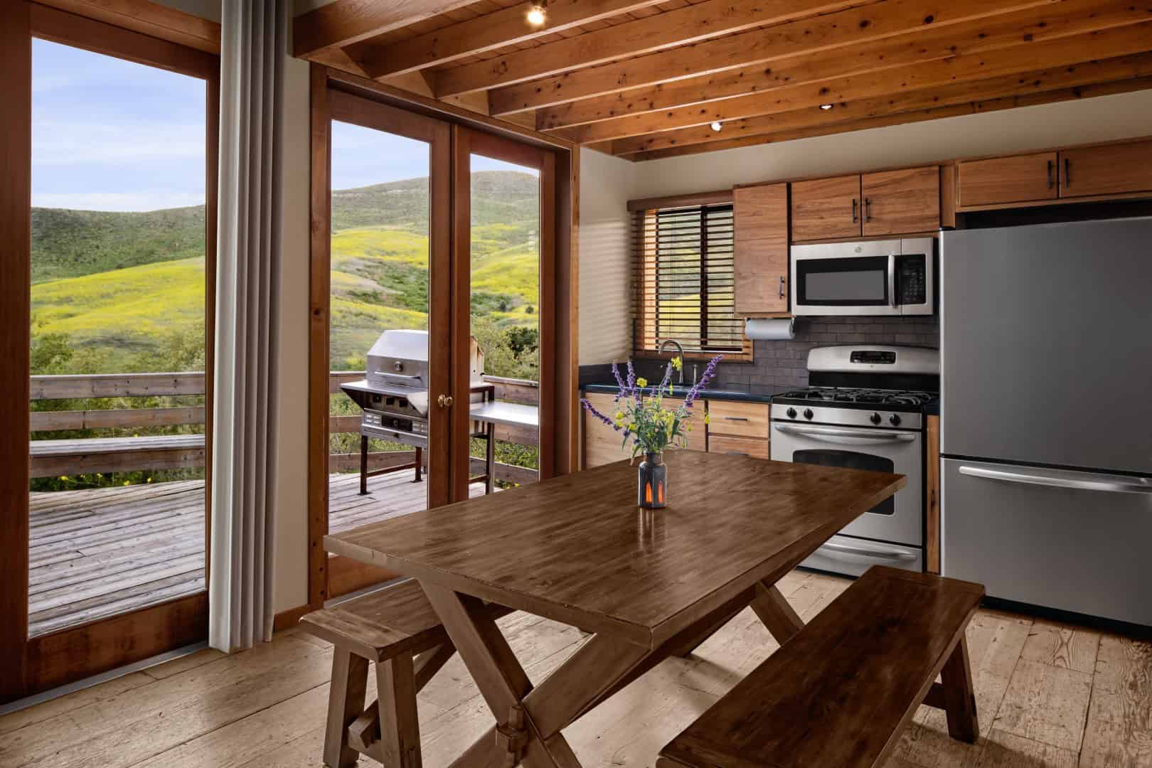 Kitchen with a range, microwave, and refrigerator, and a wood table by doors to a deck