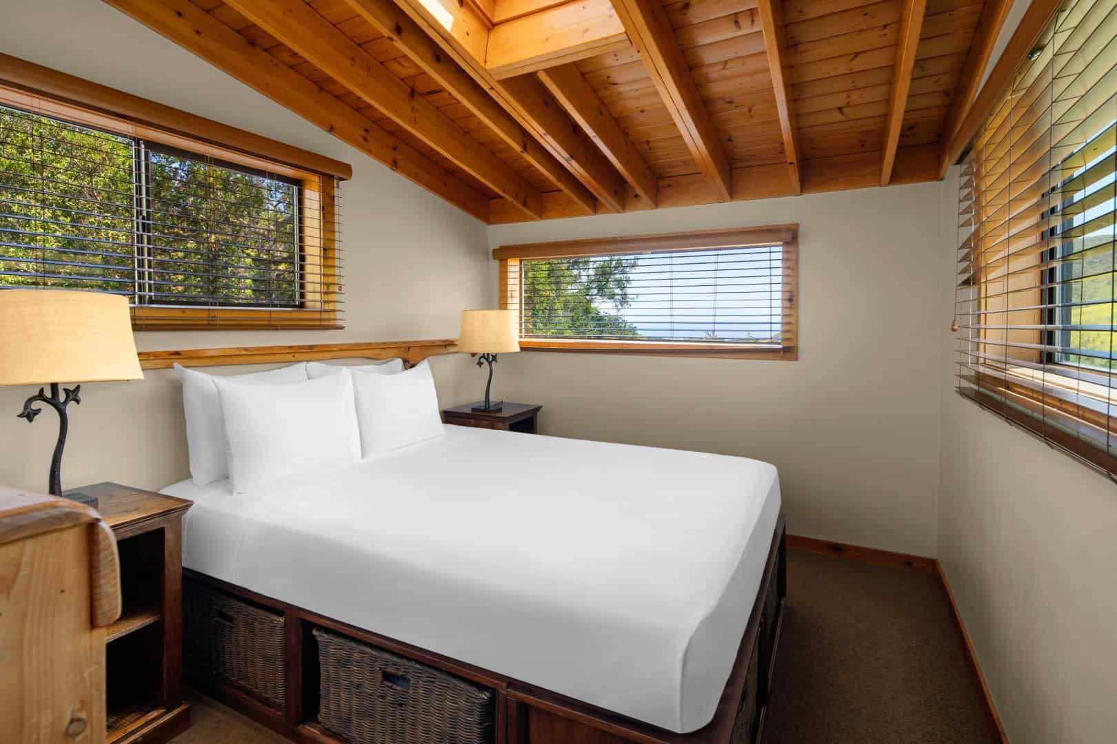 Bedroom under a wood ceiling with windows onto trees