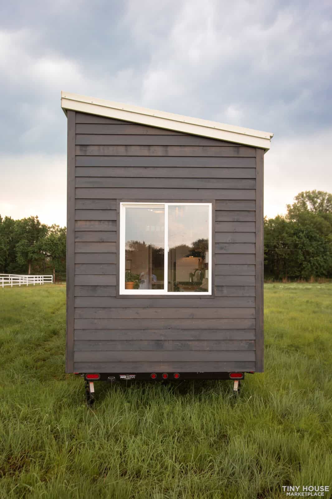 Portable tiny house with dark gray siding and a large window.