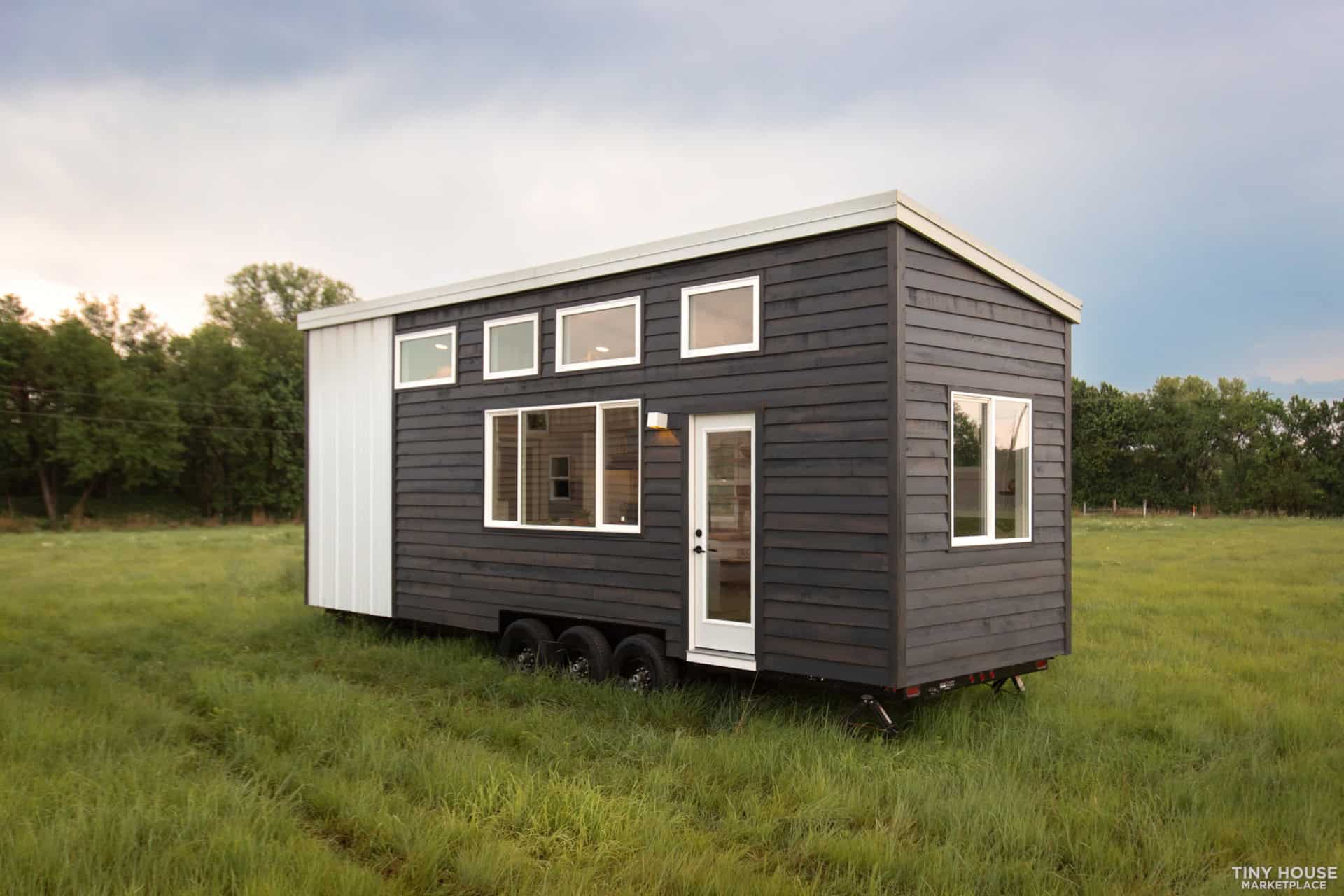 Tiny house on wheels with sleek black exterior and spacious windows for natural light.