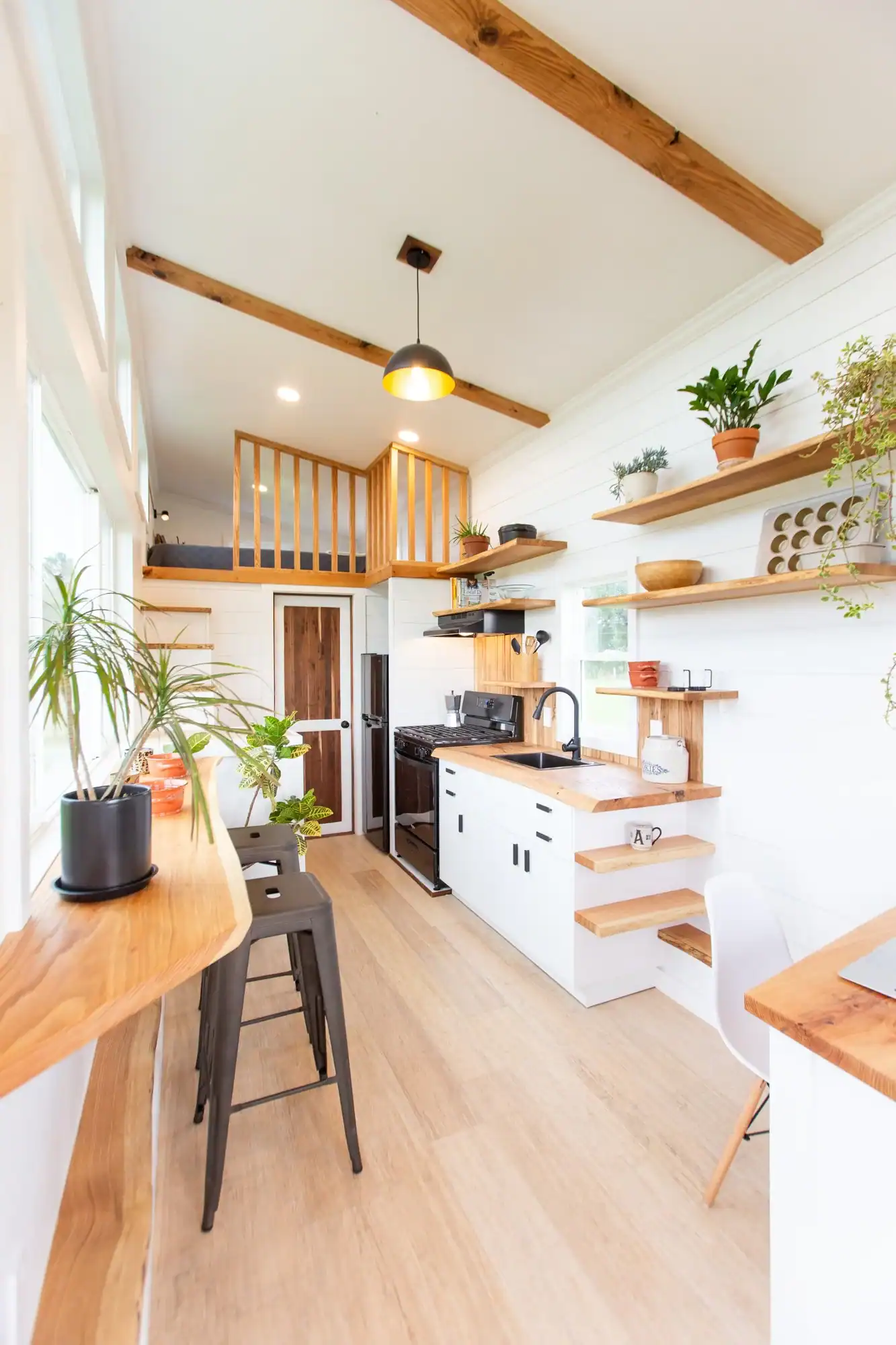Bright tiny house kitchen featuring wooden accents and open shelving.