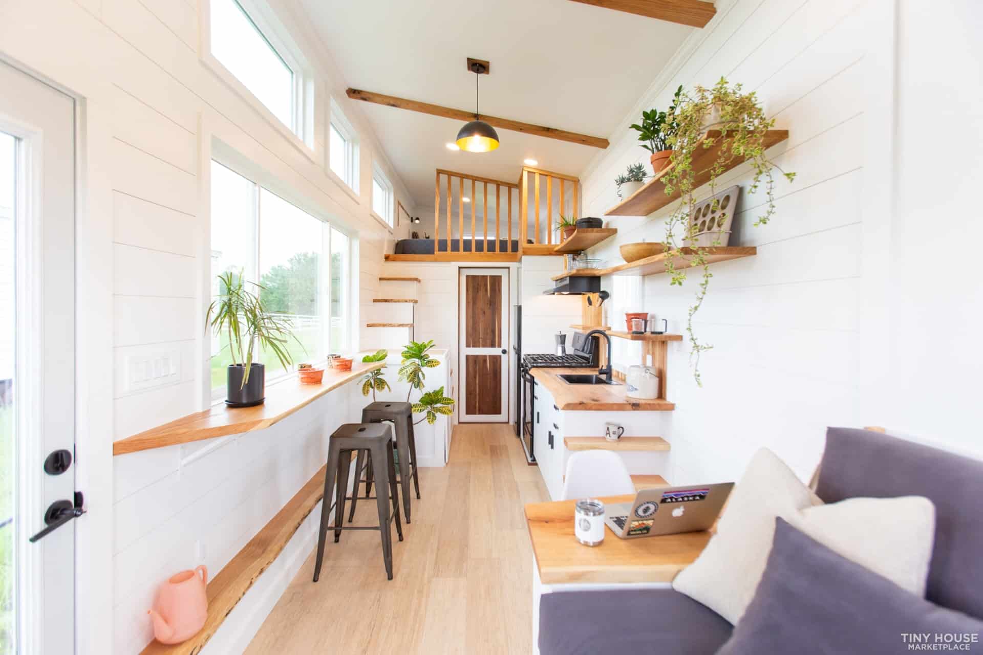 Bright interior of a tiny house with large windows and cozy furnishings.