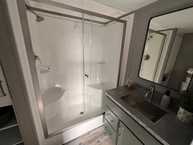 Bathroom with a glass-door shower and a vanity with a large mirror