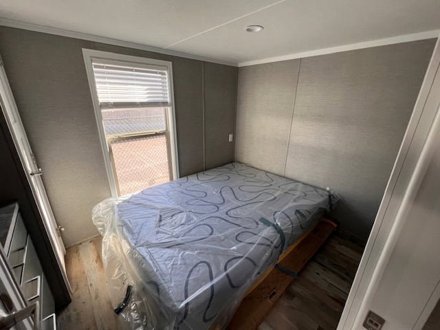 Main-floor bedroom with a new mattress still in its plastic wrap below a tall window
