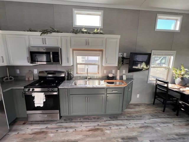 Kitchen in the Elevation Woodland Loft with green lower cabinets, white upper cabinets, a gas range and microwave
