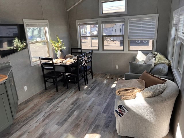 Furnished living and dining area with a sofa, a dining table for four and a wall of windows