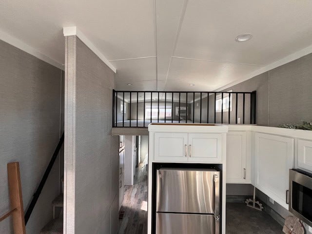 Upper loft with a black railing above the kitchen
