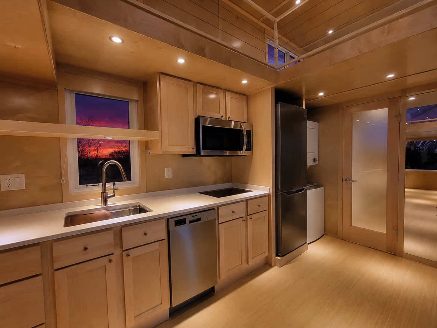Angled view of the Escape eONE Limited kitchen at dusk with warm lighting and a sunset window over the sink