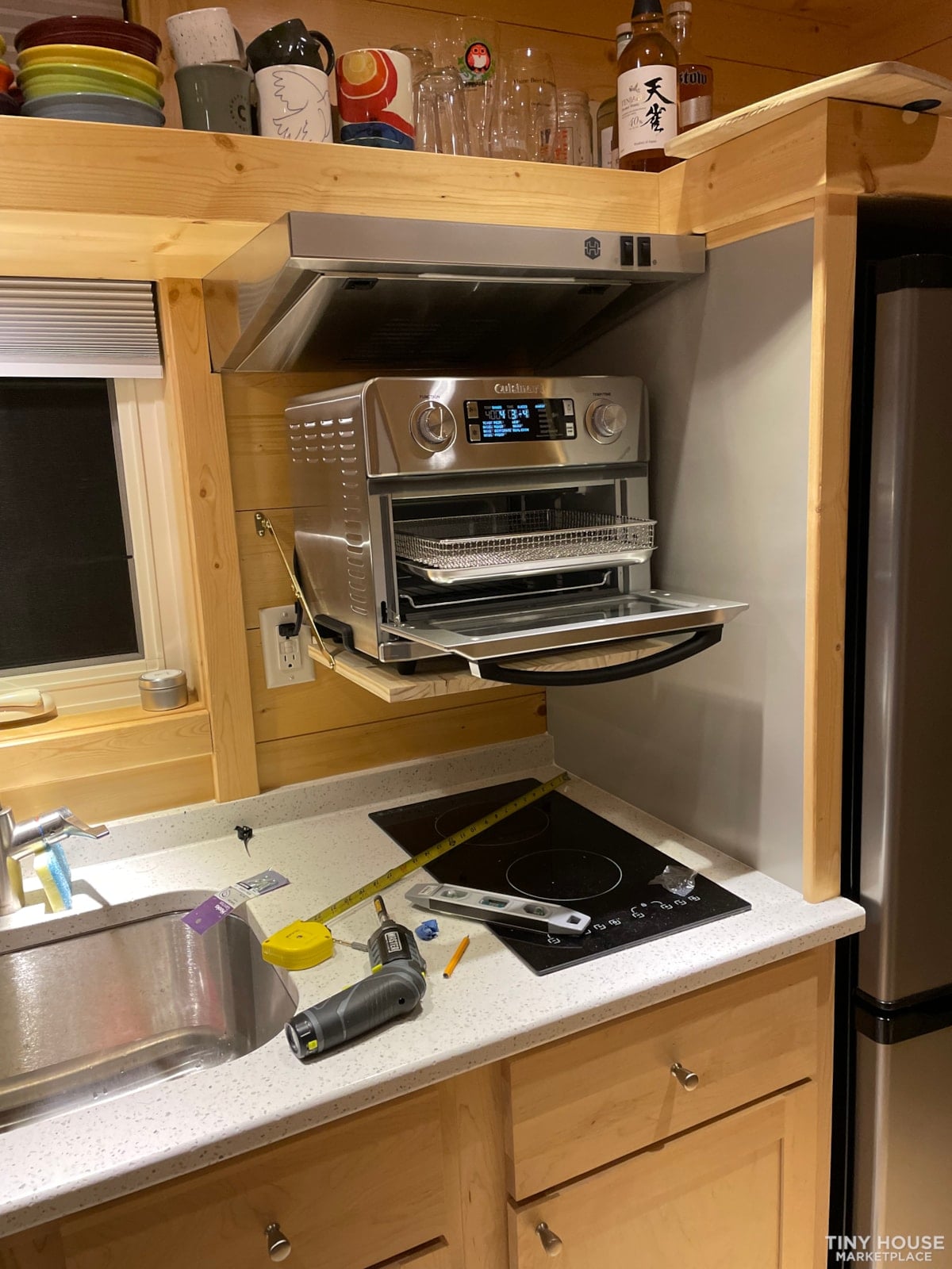 Countertop air fryer oven sitting on the fold-down shelf under the kitchen range hood