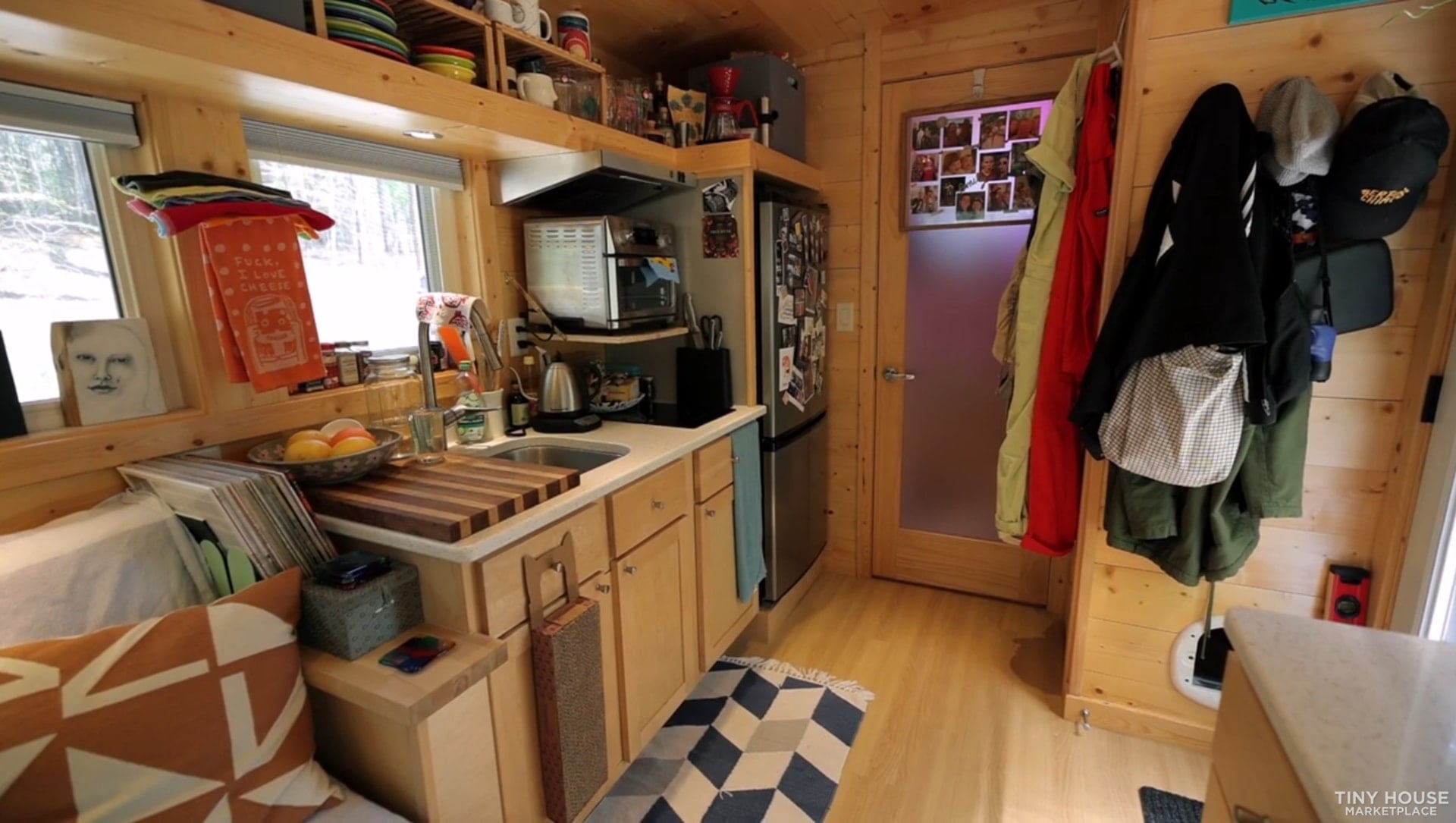 Galley kitchen looking toward the frosted bathroom door with coat hooks by the entry