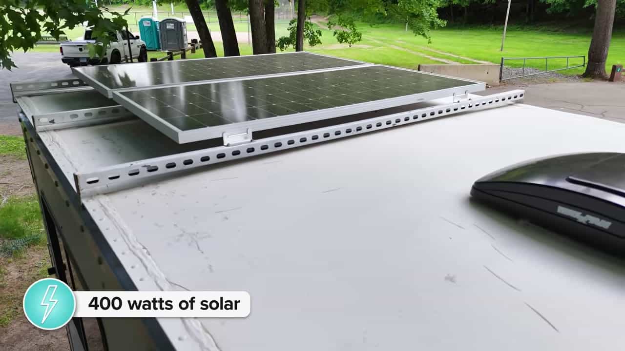 Two solar panels on roof rails of Box Truck Betti labeled 400 watts of solar with a roof vent nearby