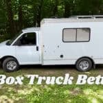 White Box Truck Betti tiny home parked in the woods with rooftop solar panels and spare tire