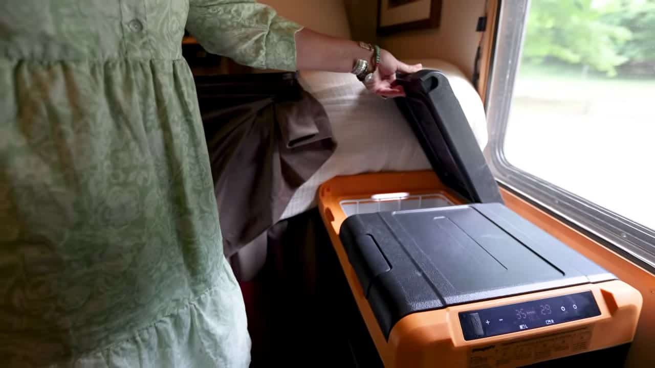 Eva opening a BougeRV dual-zone orange portable fridge freezer inside her box truck tiny home