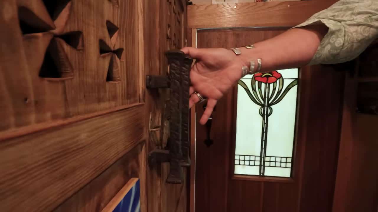 Hand-forged metal handle on a carved wooden door with stained-glass red poppy panel inside Box Truck Betti