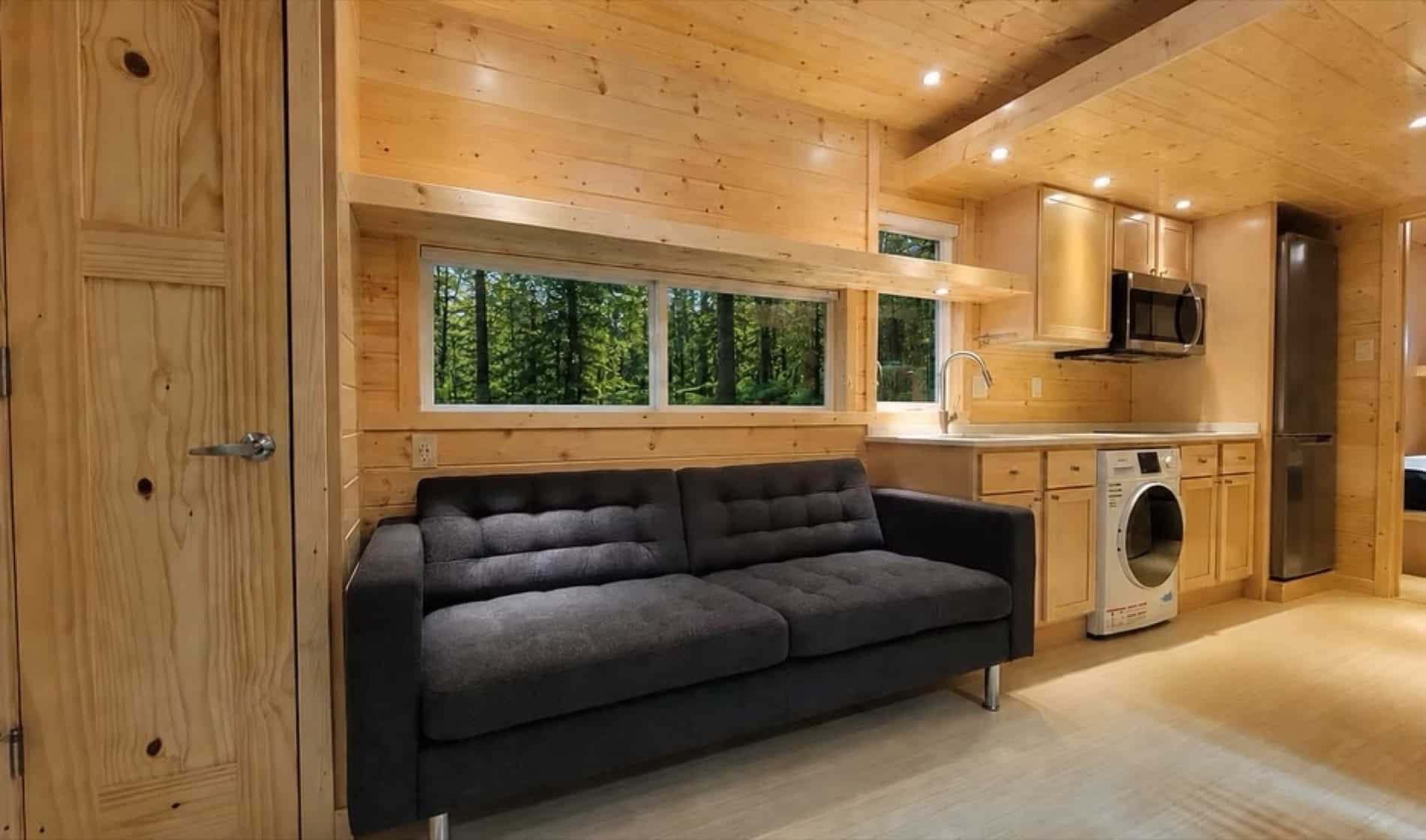 Living room with sofa and forest view window in the eVista King Limited tiny house
