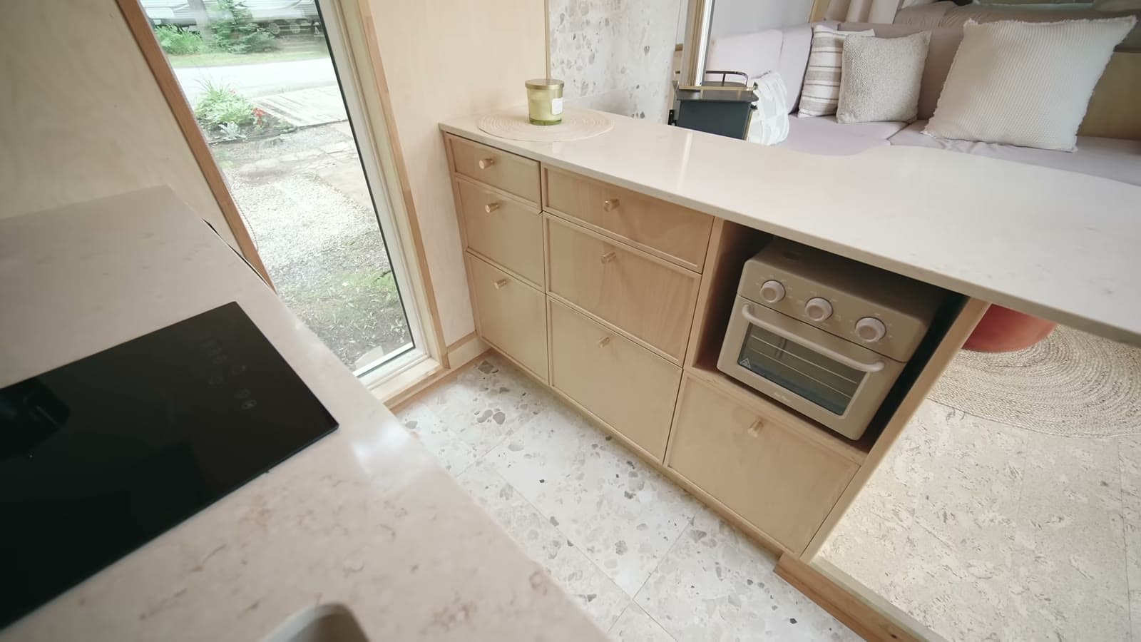 B.Drop.24f kitchen with quartz counter, flush black cooktop, birch drawer fronts and a toaster oven set into the cabinetry