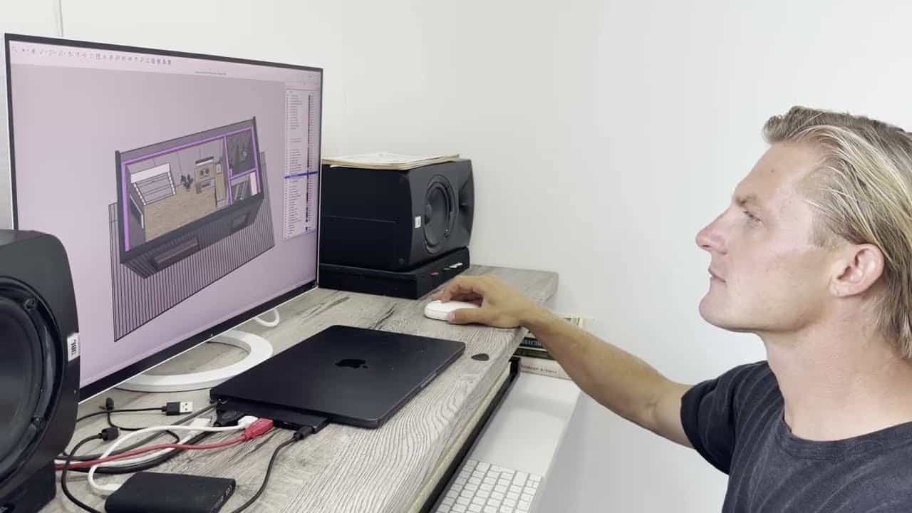 Workspace desk with a monitor showing a 3D interior model, speakers, and laptop