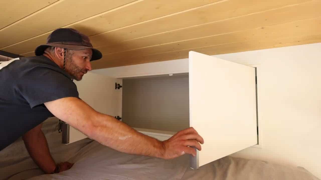 Loft built-in cabinet open above the queen bed, wood-plank ceiling