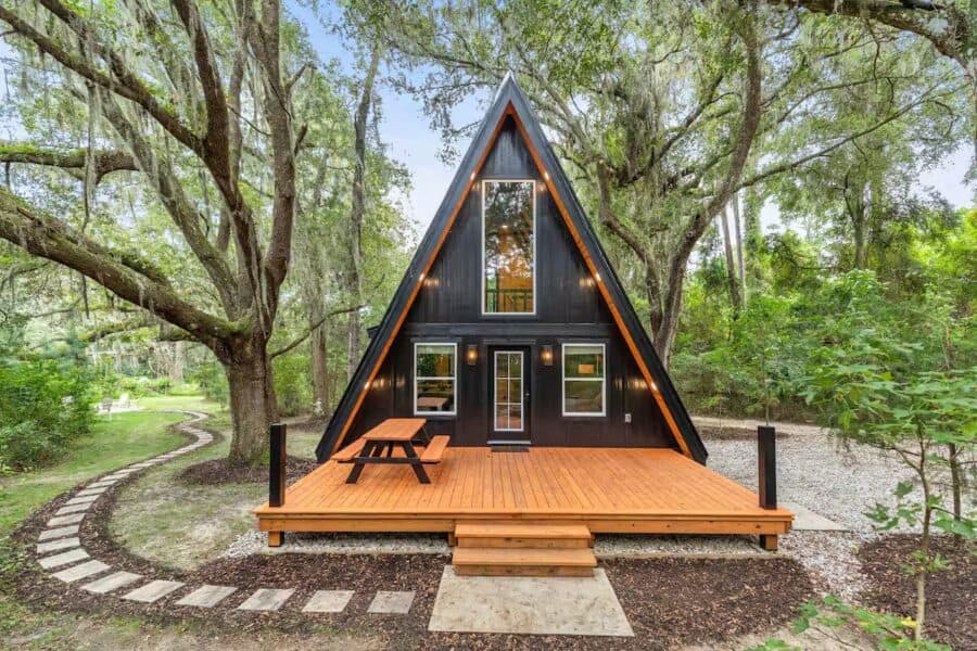 Charming A-frame tiny house nestled among lush trees in Florida, perfect for small space living and.